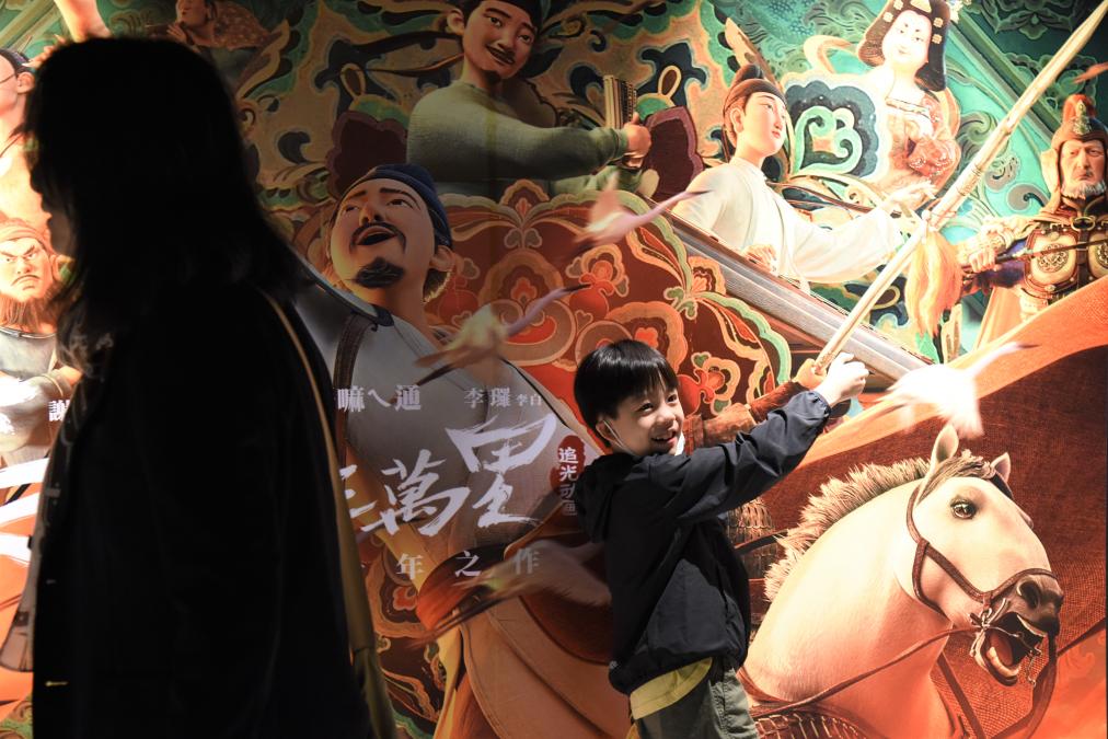 4月28日,观众在电影海报前拍照。新华社记者 刘斐 摄